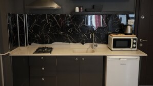 A compact kitchen with a black marble backsplash, a microwave, a gas stove, a sink, and a dishwasher. - BRK DREAM SUITS (Istanbul)