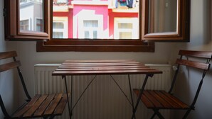 A room with a table and two chairs, a window with a view of buildings, and a radiator. - BRK DREAM SUITS (Istanbul)
