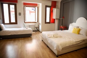 Ein Hotelzimmer mit zwei Betten, einem kleinen Tisch, einem Stuhl und einem Fenster mit Jalousien.