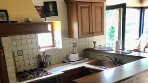 Eine Küche mit Holzausstattung, einem Gasherd, einem Geschirrspüler, einer Wand mit Backsteinoptik und einem Fenster für natürliches Licht.