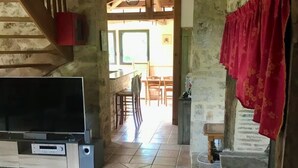 Ein rustikales Interieur mit einer Holztreppe, einem Fernseher und einem Kamin aus Stein.