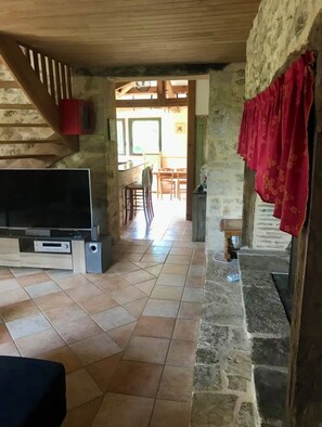 Ein rustikales Interieur mit einer Holztreppe, einem Fernseher und einem Kamin aus Stein.
