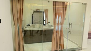 Un baño con paredes de vidrio, que incluye una bañera, una zona de ducha y una puerta de vidrio con cortinas.