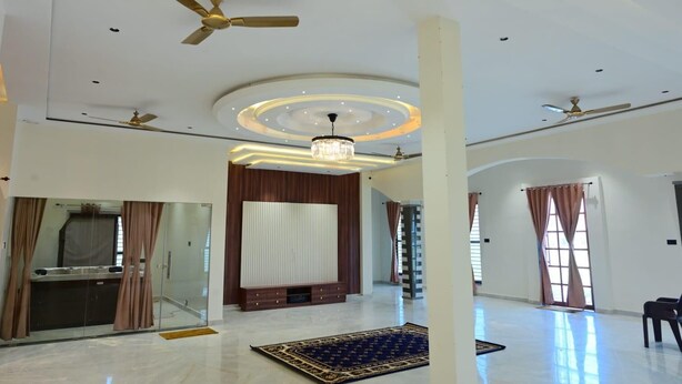 Una habitación amplia con techo alto, ventiladores de techo, un candelabro y un gran ventanal con cortinas.