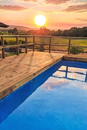 A wooden deck with a swimming pool, surrounded by a natural landscape and a sunset. - Tuscia Prestige by Interhome (Orte)