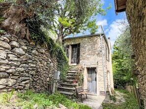 A stone building with a wooden bench, a small staircase, and a door. - Laetitia by Interhome (Pieve di Teco)