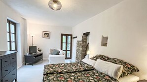 Een slaapkamer met een bed, een dressoir, een televisie en een stenen muur.