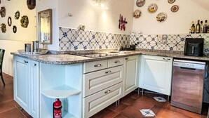 Een keuken met witte kasten, een betegelde spatwand en diverse keukenapparaten.