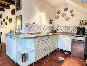 A kitchen with white cabinets, a tiled backsplash, and various kitchen appliances. - Laetitia by Interhome (Pieve di Teco)