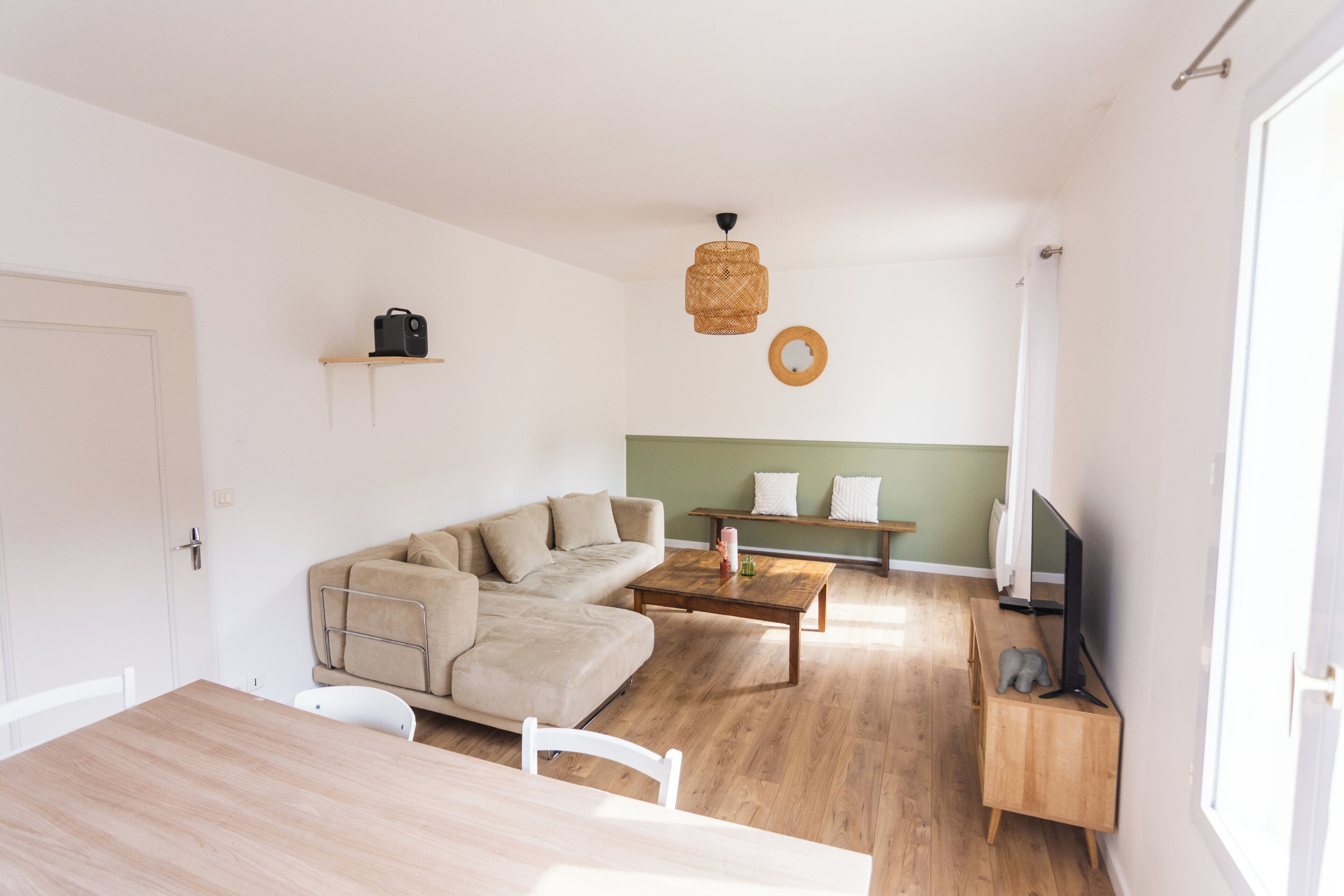 A modern living space with a sofa, coffee table, TV stand, and a dining table.