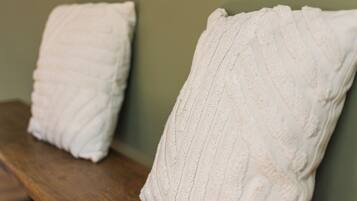 Two white pillows on a wooden bench against a green wall.