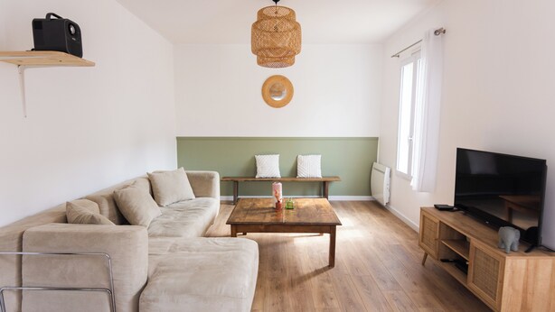 Un soggiorno moderno con divano, tavolino, mobile TV e lampadario.
