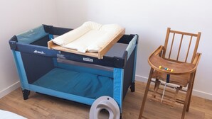 Una culla per neonati blu e nera con materasso e una sedia di legno con giocattoli.