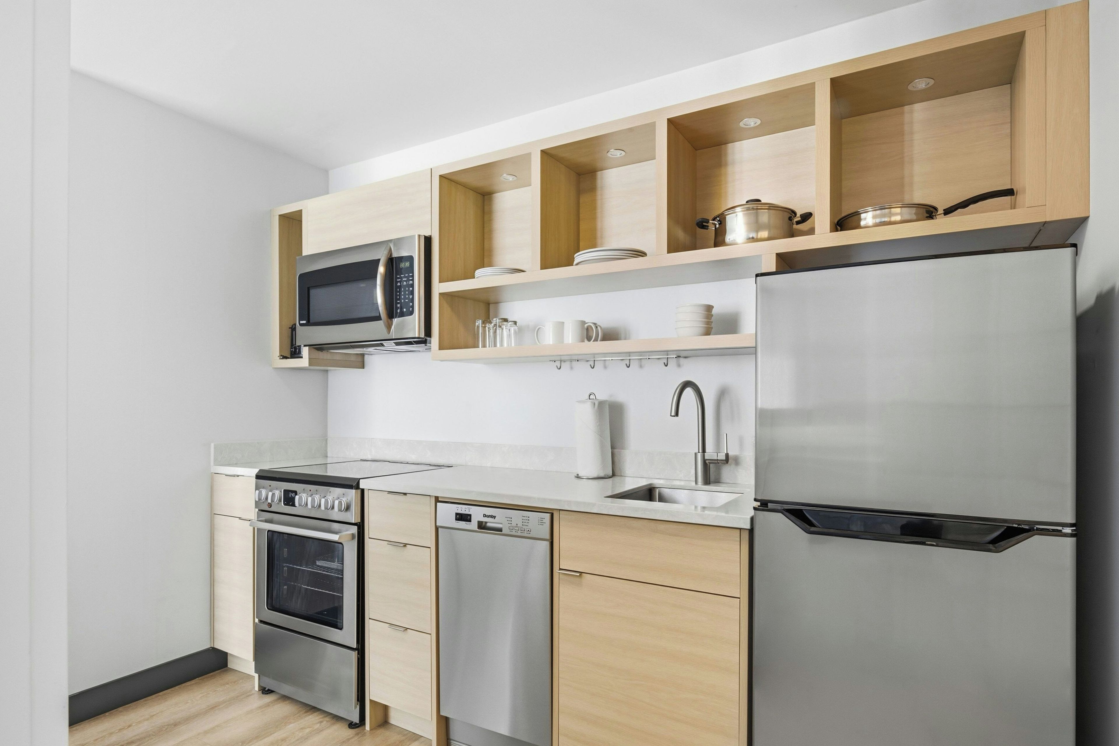 Una cocina moderna con electrodomésticos de acero inoxidable, armarios de madera y un microondas integrado.