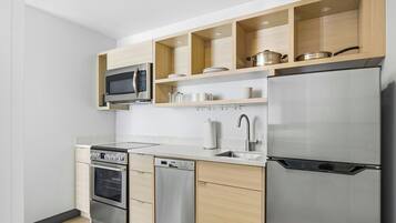 Una cocina moderna con electrodomésticos de acero inoxidable, armarios de madera y un microondas integrado.