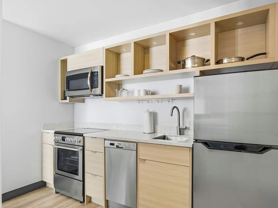 A modern kitchen with stainless steel appliances, wooden cabinets, and a built-in microwave.