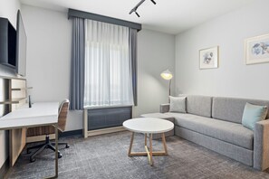 A modern hotel room with a desk, chair, sofa, and a round table. - TownePlace Suites by Marriott Vaughan (Vaughan)