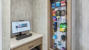 Escritorio con monitor, teclado y un organizador de pared tipo panel perforado que contiene diversos artículos de aseo personal.