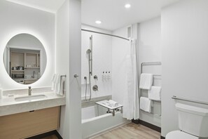 Un baño moderno con ducha integrada, tocador con espejo y un inodoro.