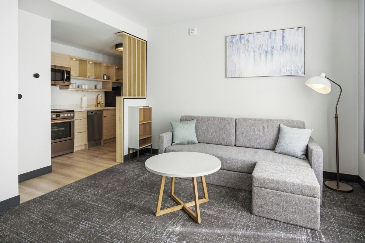 A modern living room with a gray sectional sofa, a round white coffee table, and a floor lamp.