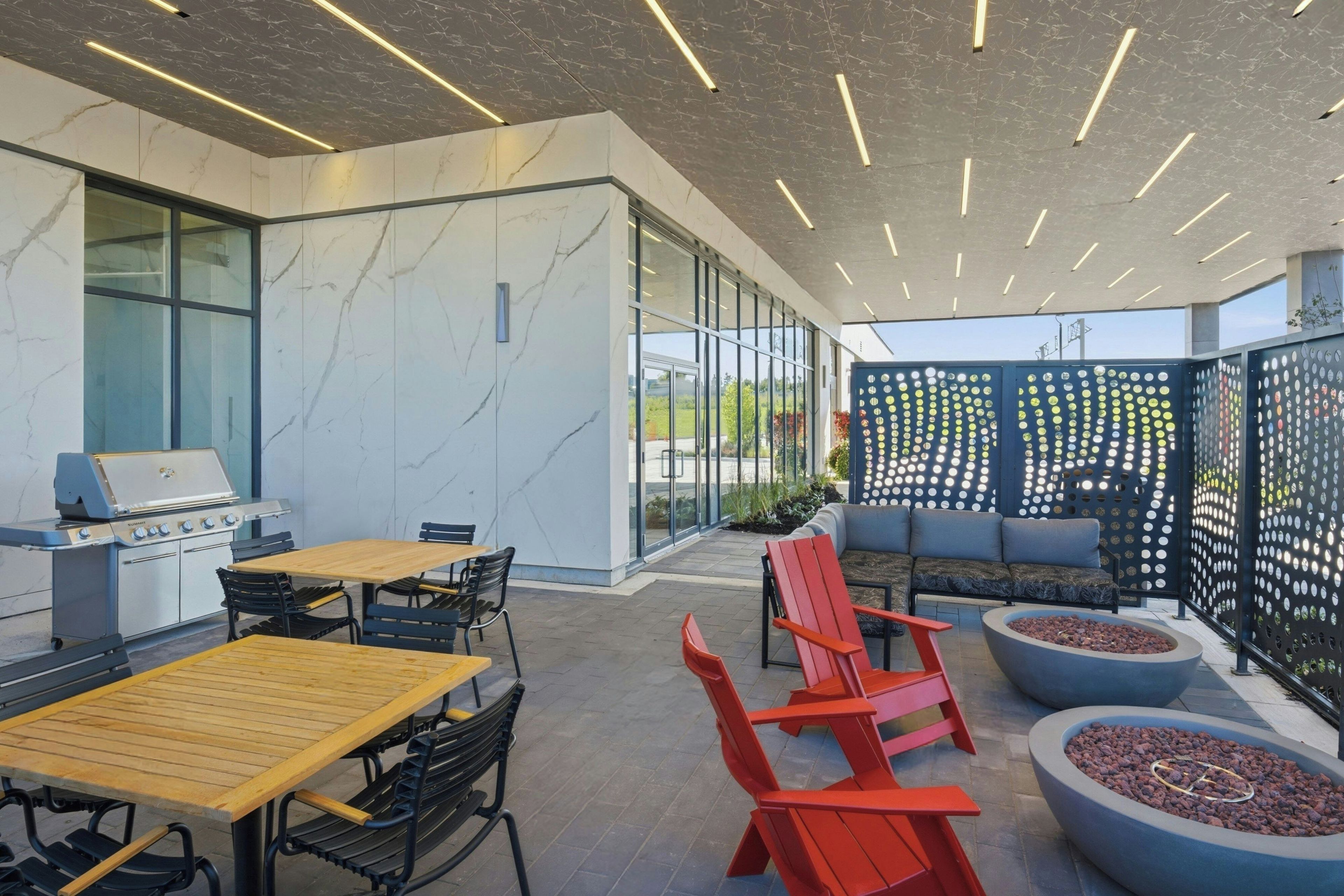 Un espacio patio al aire libre con una parrilla, asientos y una valla decorativa.