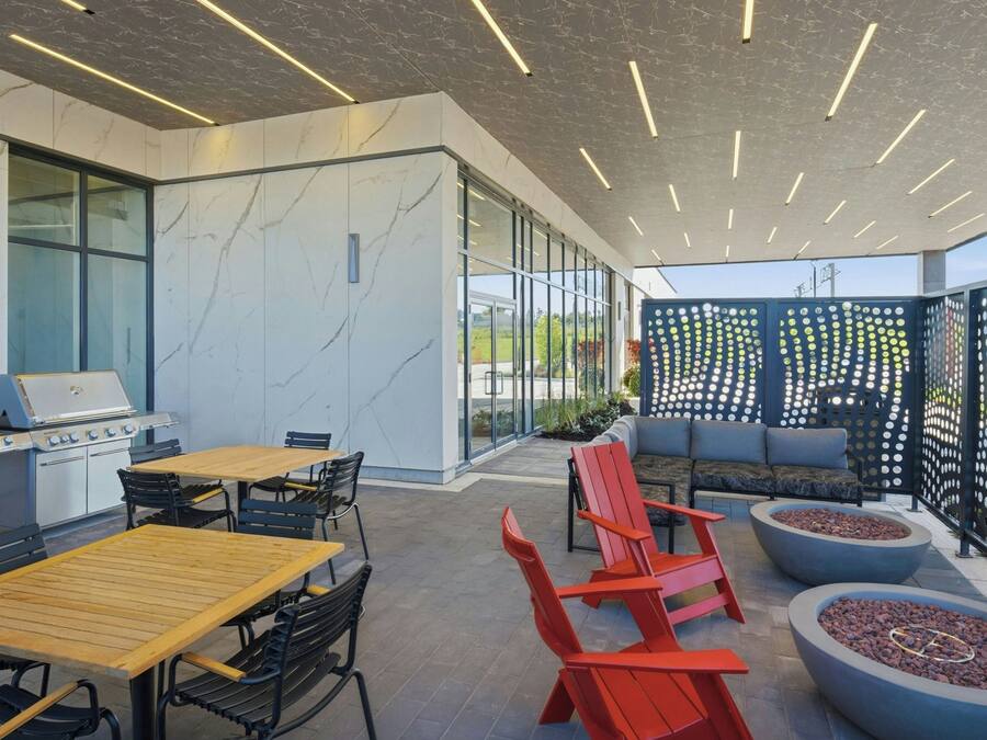 Un espacio patio al aire libre con una parrilla, asientos y una valla decorativa.