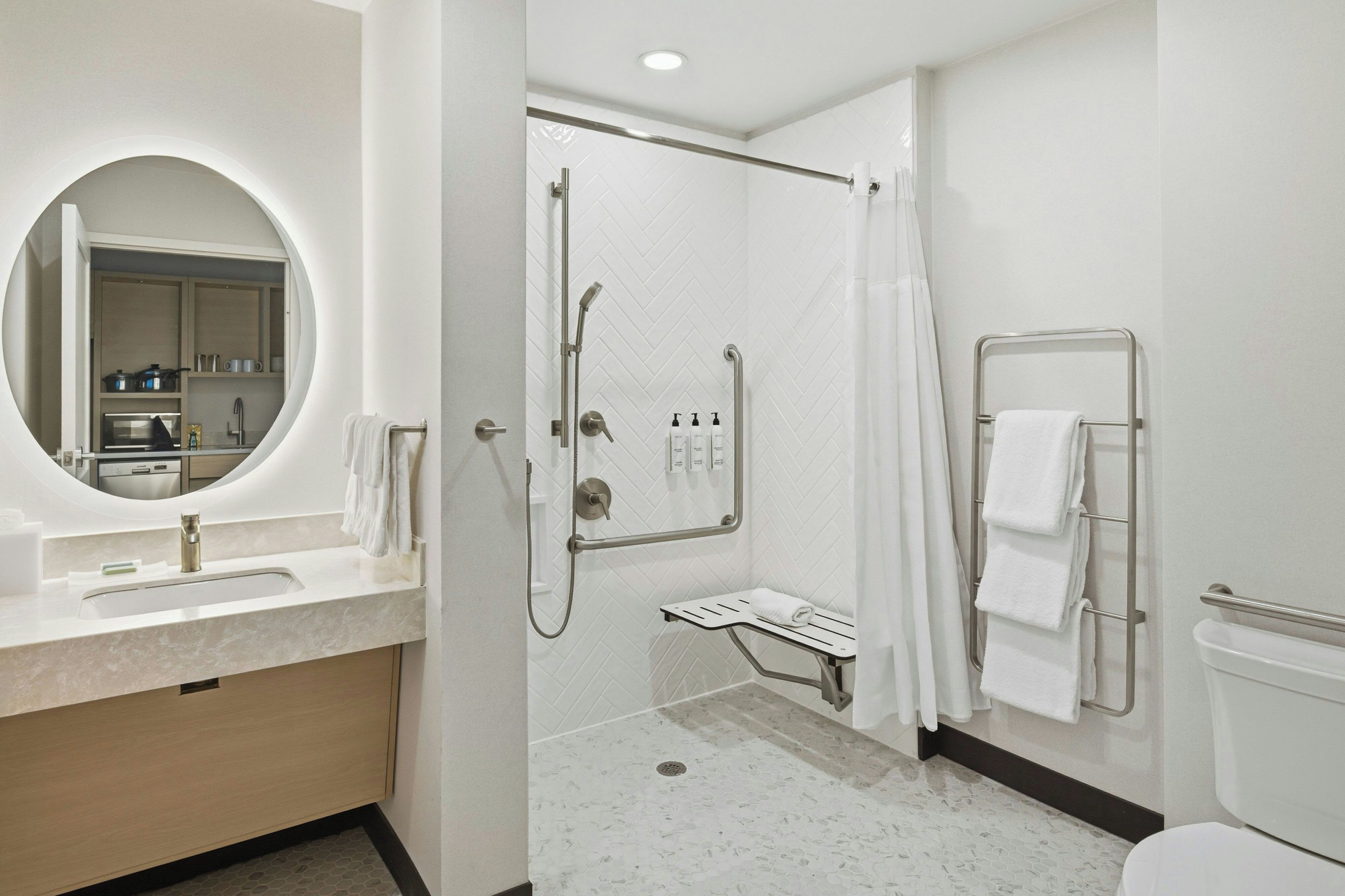 A modern bathroom with a sink, mirror, shower, and toilet.
