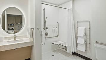 A modern bathroom with a sink, mirror, shower, and toilet.