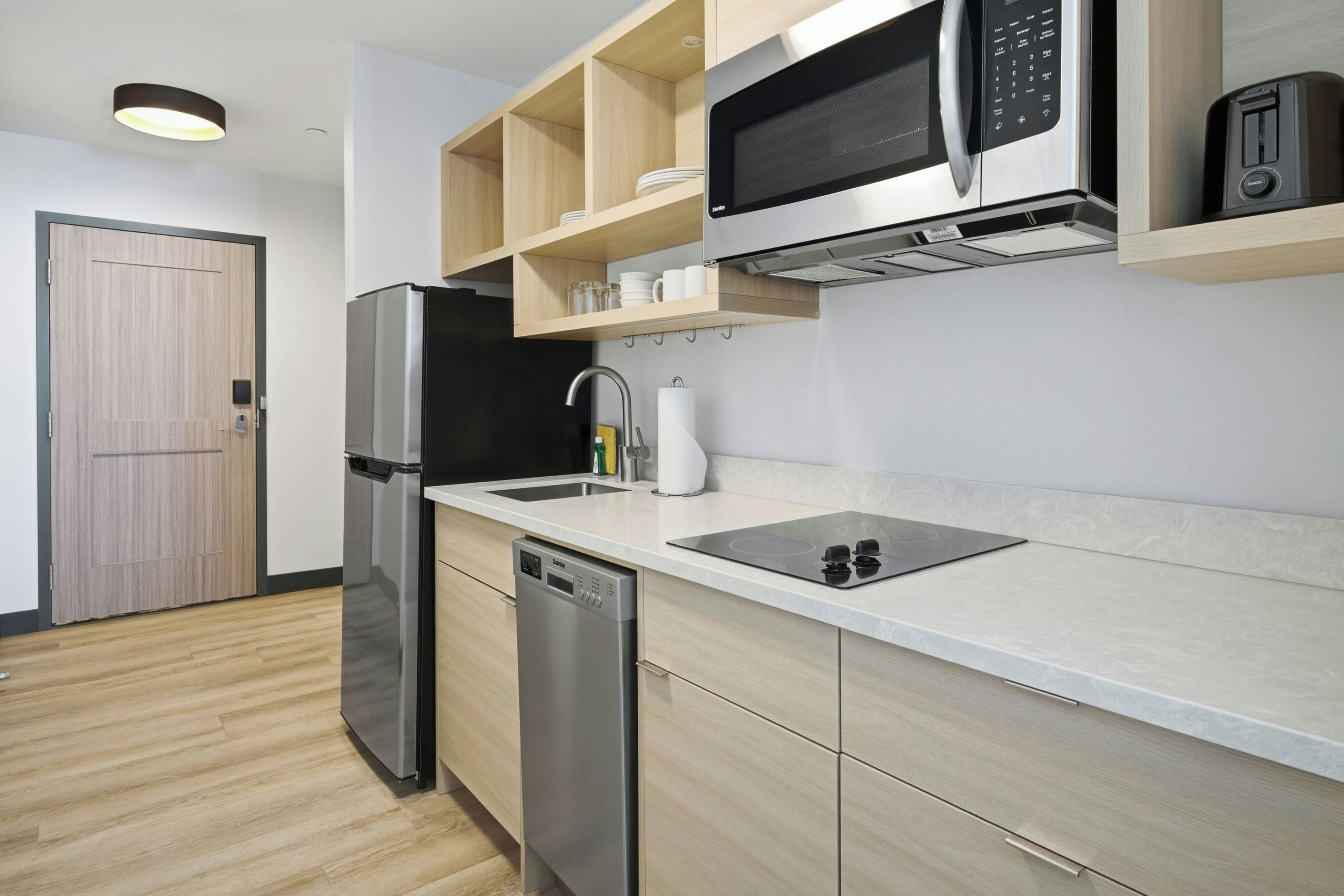 A modern kitchen with a stainless steel refrigerator, a built-in dishwasher, a microwave, and a sink with a faucet.