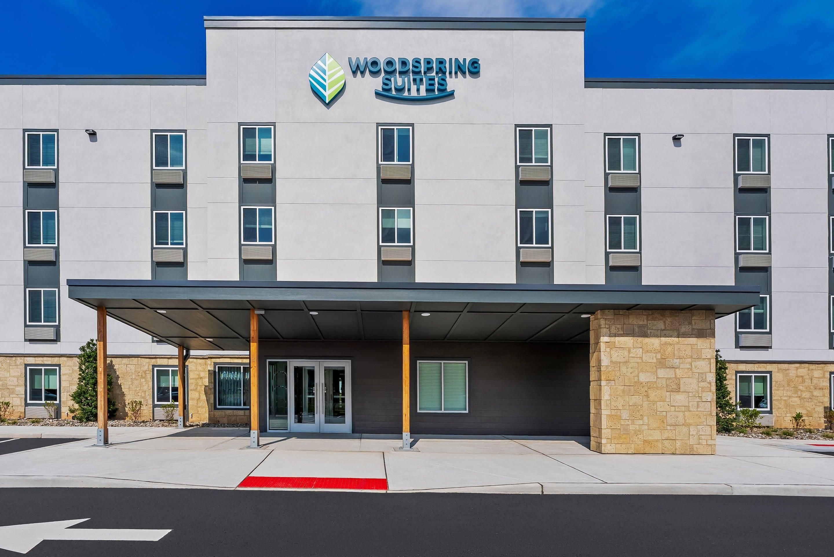 Ein mehrstöckiges Hotel mit schlichter Fassade, überdachter Eingangspartei und roter taktiler Bodenmarkierung.