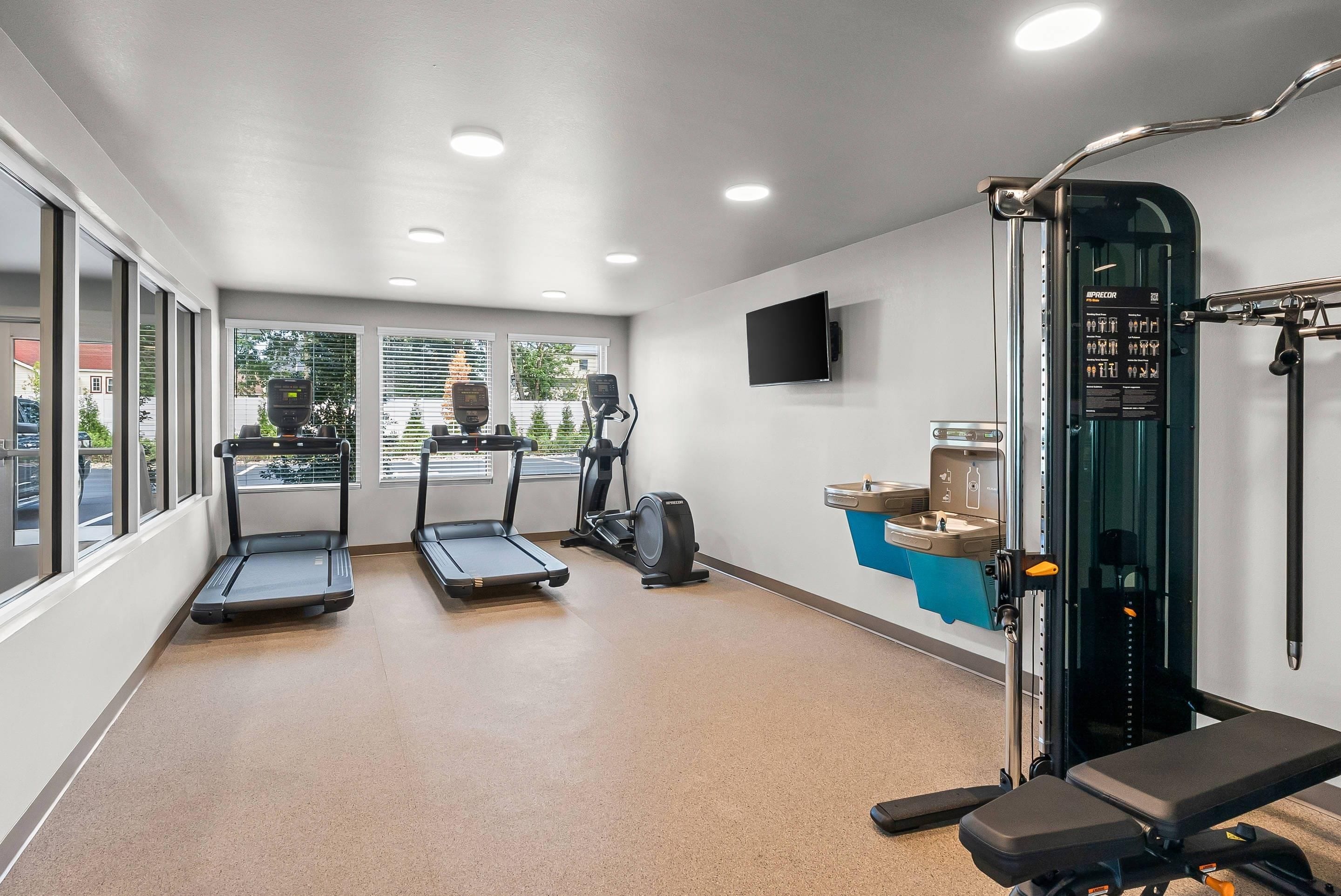 Une salle de sport équipée de tapis de course, d’un vélo d’appartement et d’une machine de musculation.