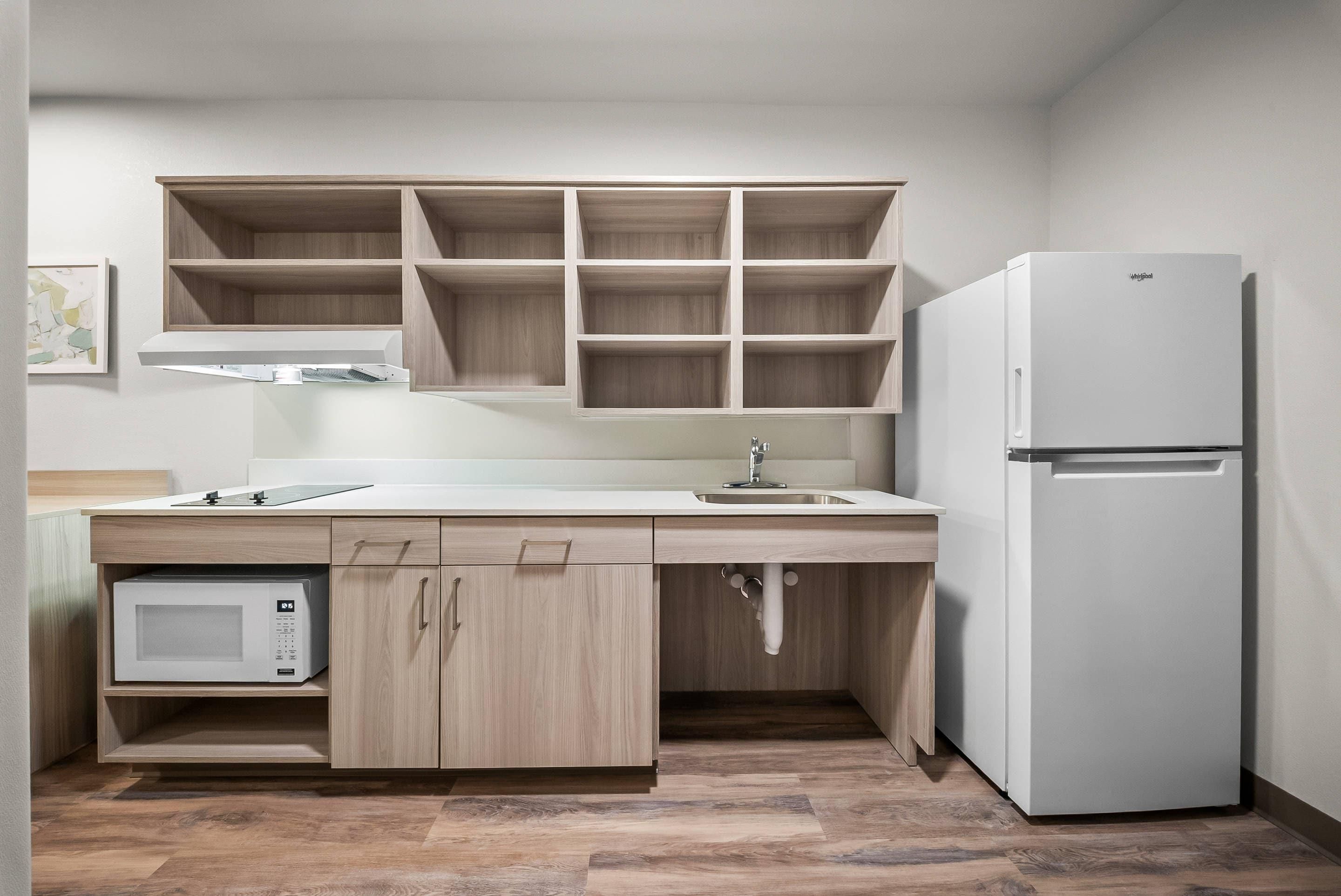 Una cocina con microondas integrado, refrigerador y armarios de madera.