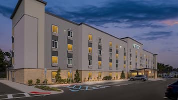 A multi-story hotel with a flat facade, multiple windows, and a parking lot with marked spaces.