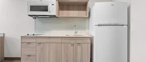 Een keuken met een magnetron, een spoelbak en een koelkast.