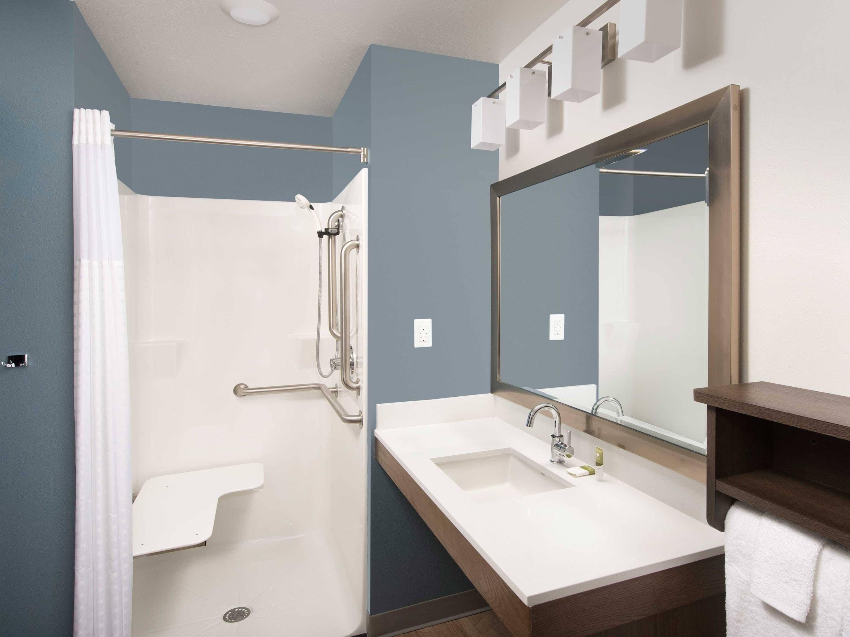 Een moderne badkamer met een douche, wastafel en een grote spiegel.