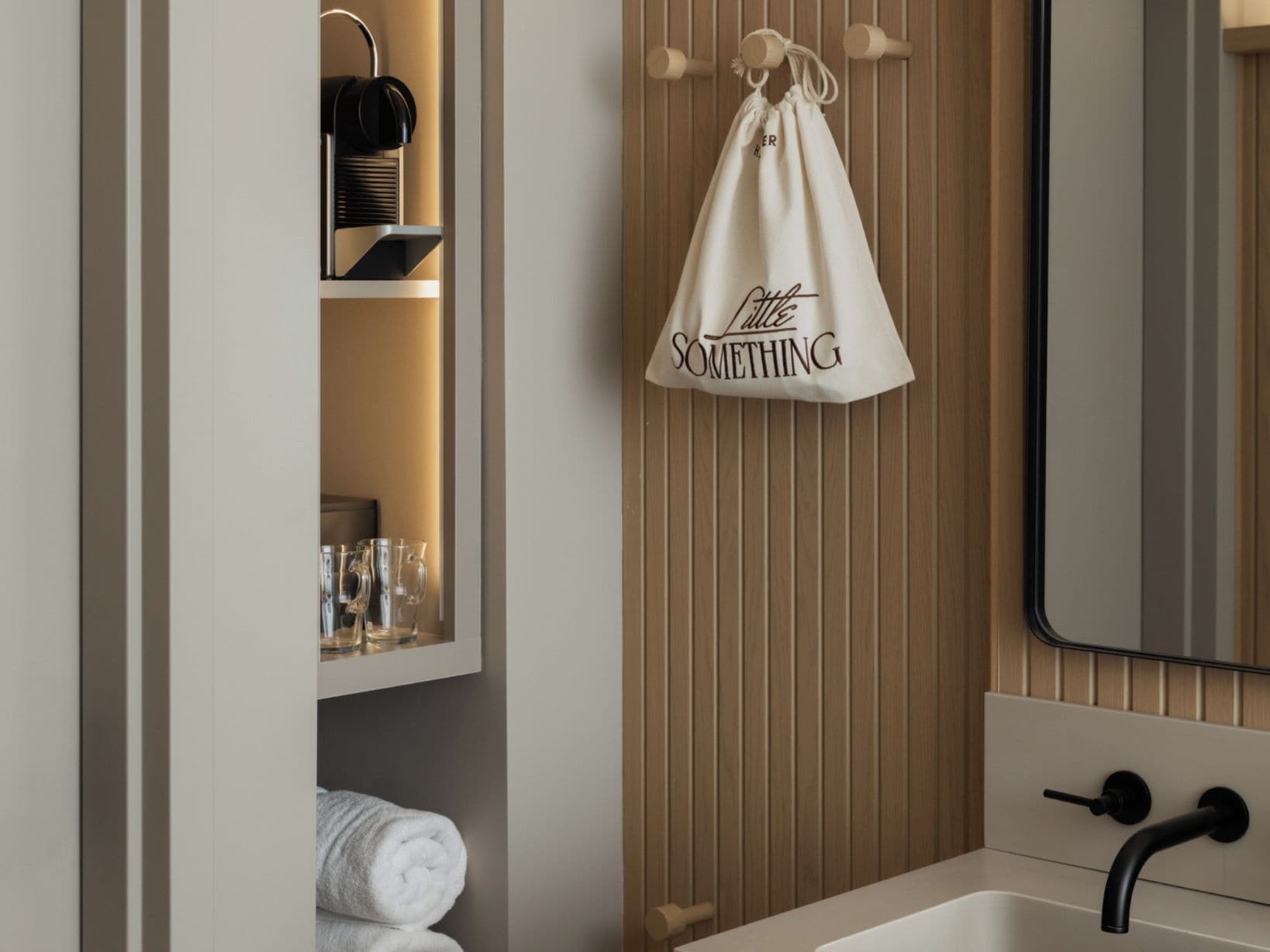 Une salle de bain avec un lavabo blanc, un miroir et un porte-serviettes sur lequel est posée une serviette blanche.