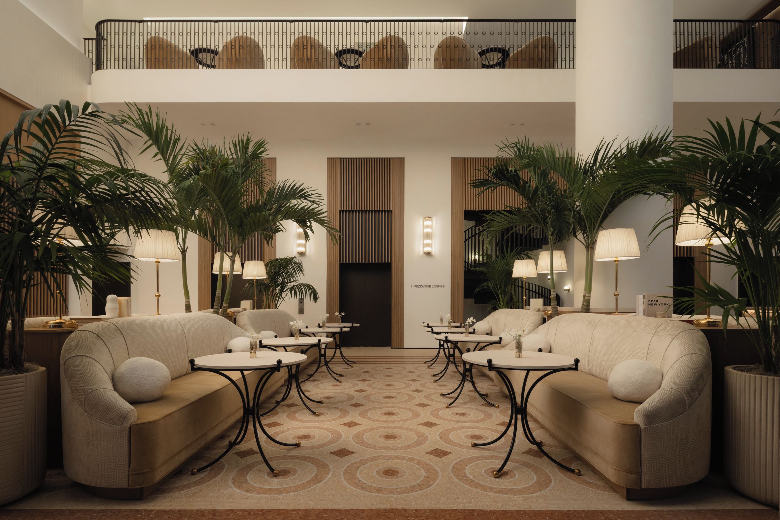 A lobby with sofas, tables, and potted plants.