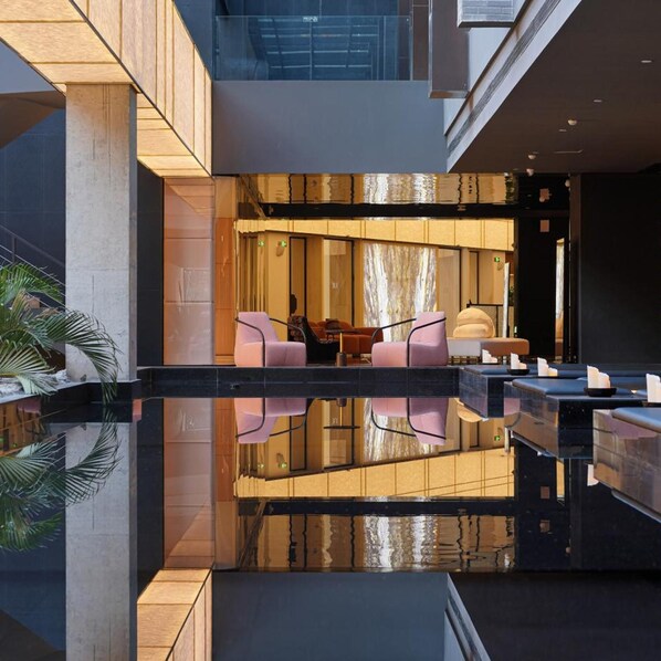 A modern lobby with a reflective pool, seating area, and a view of the interior. - TUI Blue Yangshuo Xiangheli Hotel (GUILIN)