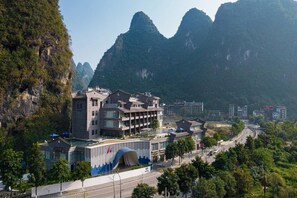 A hotel with a modern design, situated in a mountainous area with a view of the surrounding landscape. - TUI Blue Yangshuo Xiangheli Hotel (GUILIN)