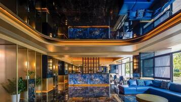Un moderno vestíbulo de hotel con un mostrador de recepción de mármol, área de descanso y ventanas amplias.