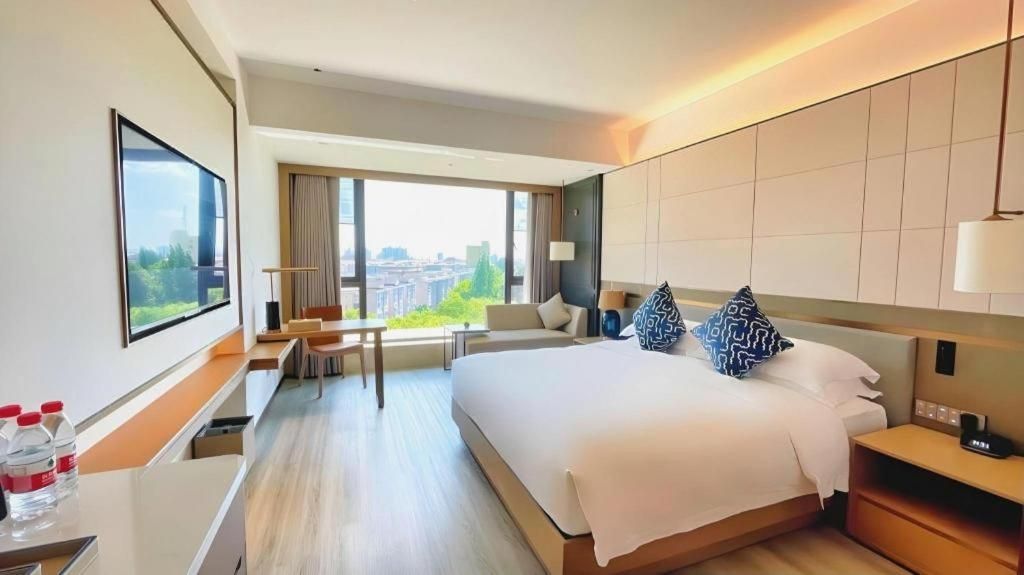 Una habitación de hotel moderna con una cama grande, un escritorio, una silla y vistas a la ciudad.