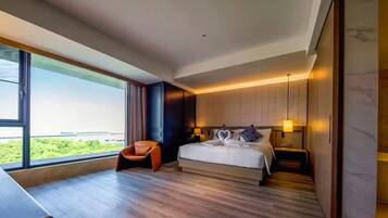 Habitación de hotel moderna con una cama grande, un escritorio y vistas a zonas verdes por la ventana.