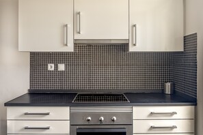 A kitchen with white cabinets, a black tiled backsplash, and a stainless steel range hood. - Downtown Riverside V by Homing (Lisbon)