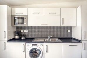 A modern kitchen with a microwave, coffee maker, sink, and washing machine. - Downtown Riverside V by Homing (Lisbon)