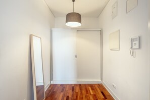 A hallway with a wooden floor, a white door, a hanging light fixture, and a wall-mounted phone. - Downtown Riverside V by Homing (Lisbon)