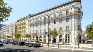 En byggnad med flera våningar, en böjd fasad, flera balkonger och ett kafé på markplan.