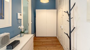 A hallway with a white wardrobe, a ceiling light, a wall-mounted thermostat, and a coat rack. - Downtown Riverside IV by Homing (Lisbon)