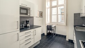 A modern kitchen with white cabinets, a black countertop, a microwave, and a coffee maker. - Downtown Riverside IV by Homing (Lisbon)