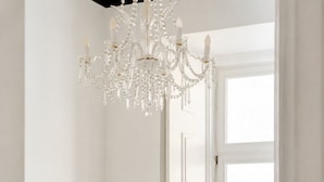 A bedroom with a bed, a chandelier, a window, and a door. - Chiado Deluxe by Homing (Lisbon)