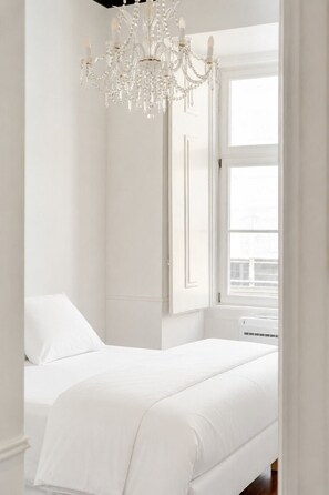 Ein Schlafzimmer mit Bett, einer Deckenleuchte, einem Fenster und einer Tür.